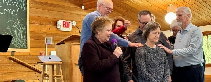 Elders laying on hands and praying for each other